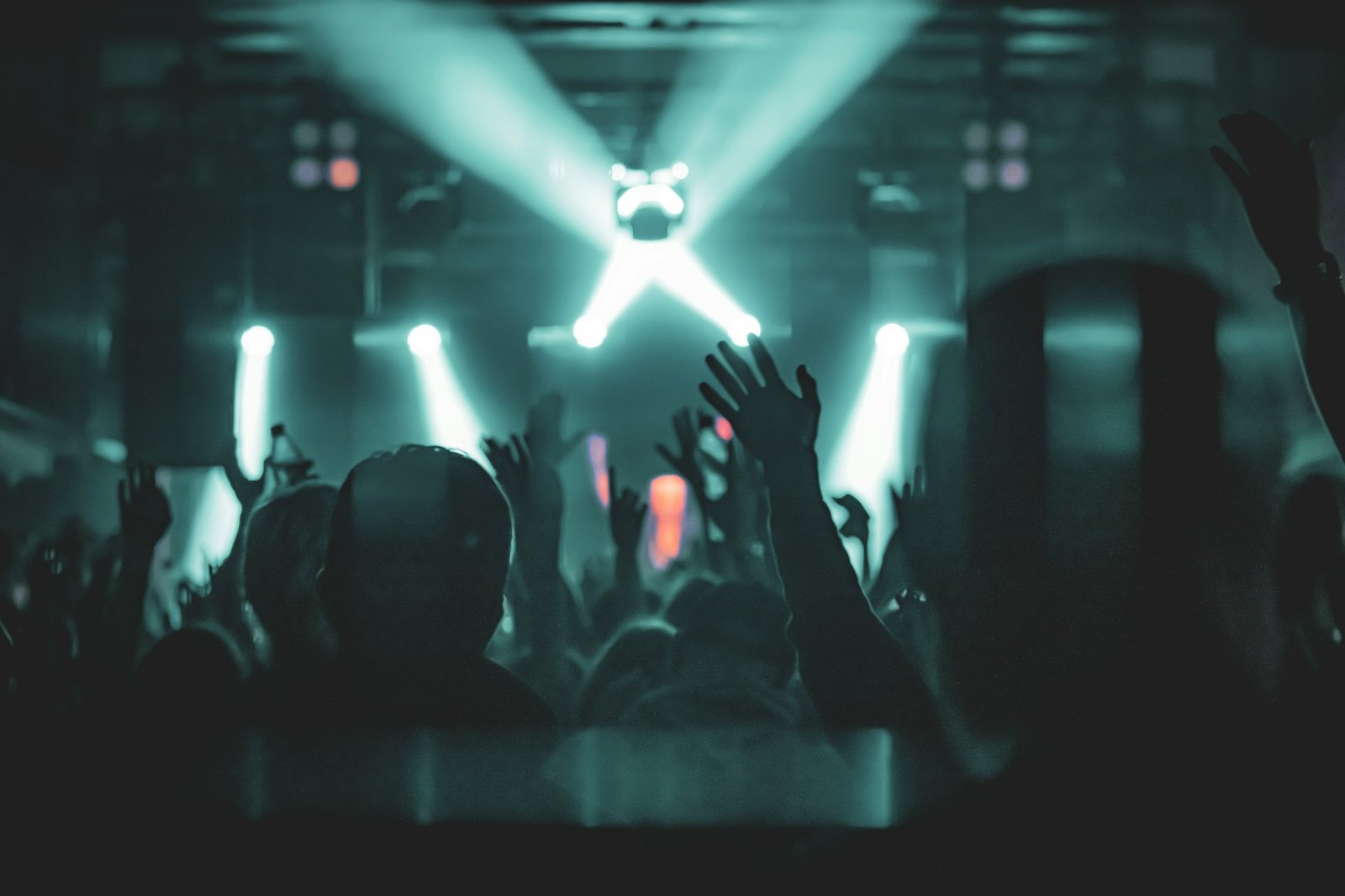 Hands raised at a concert with stage lights